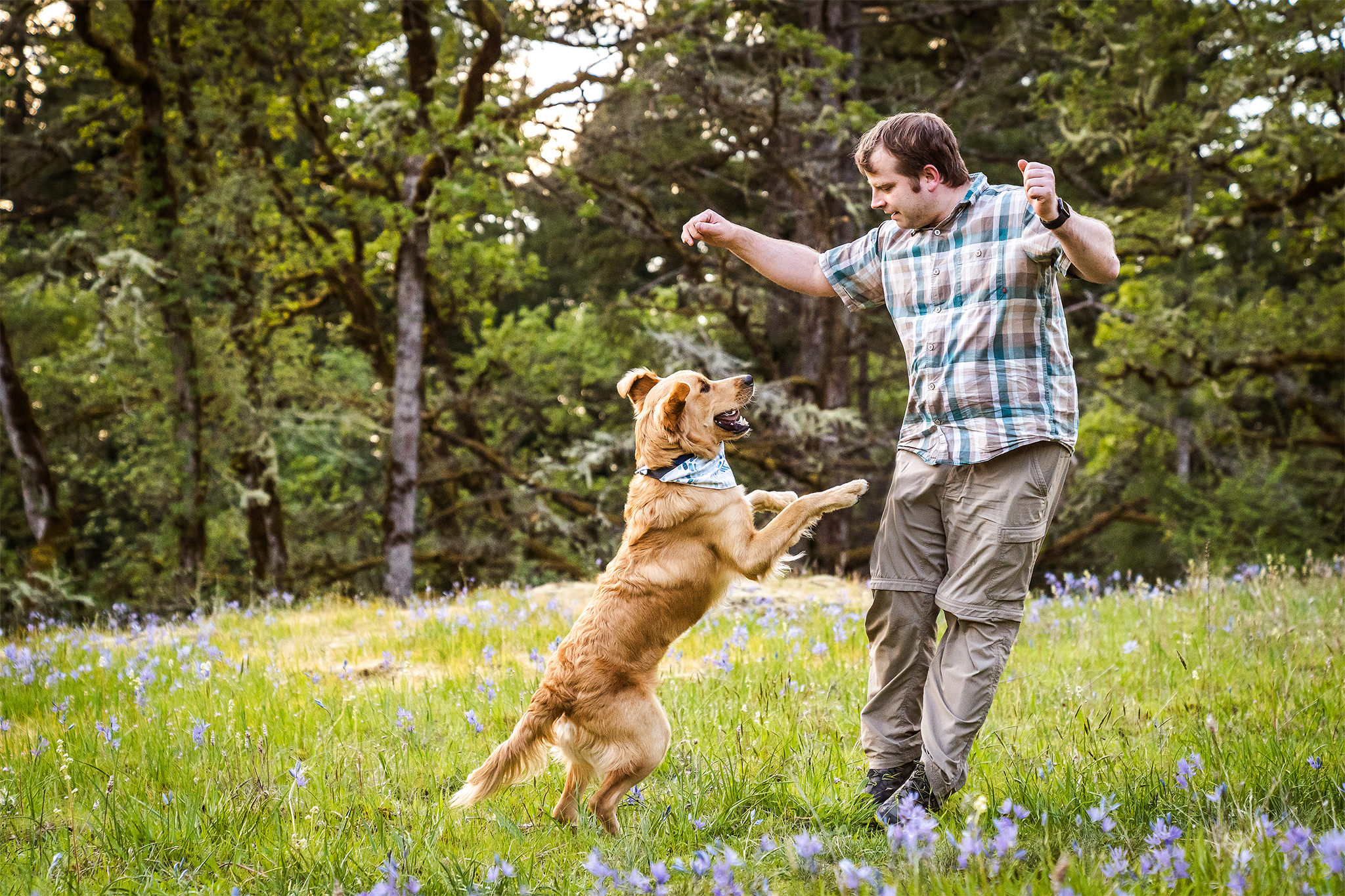 man jumps with his dog in a field