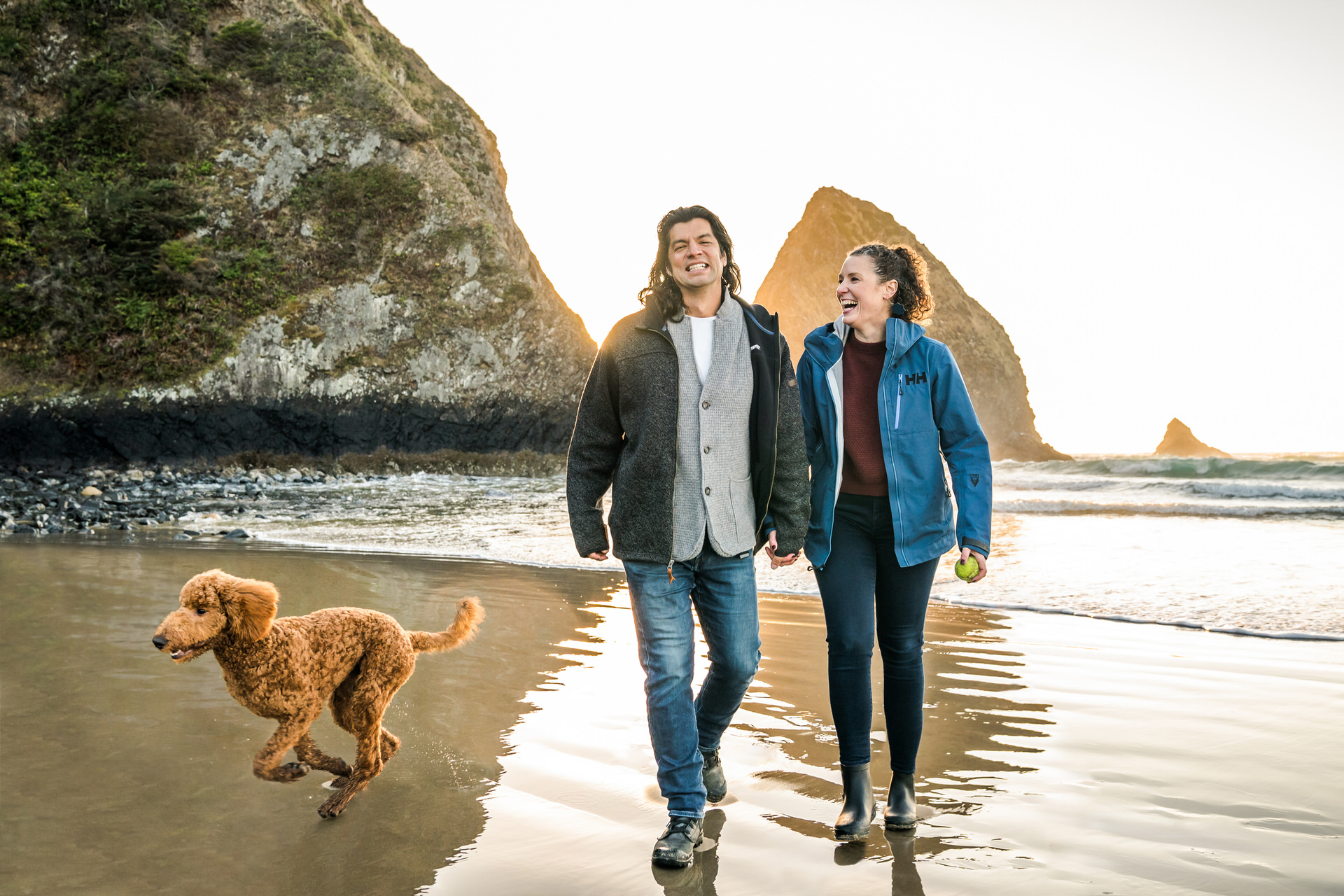 Couple at Arch Cape Oregon beach with dog running