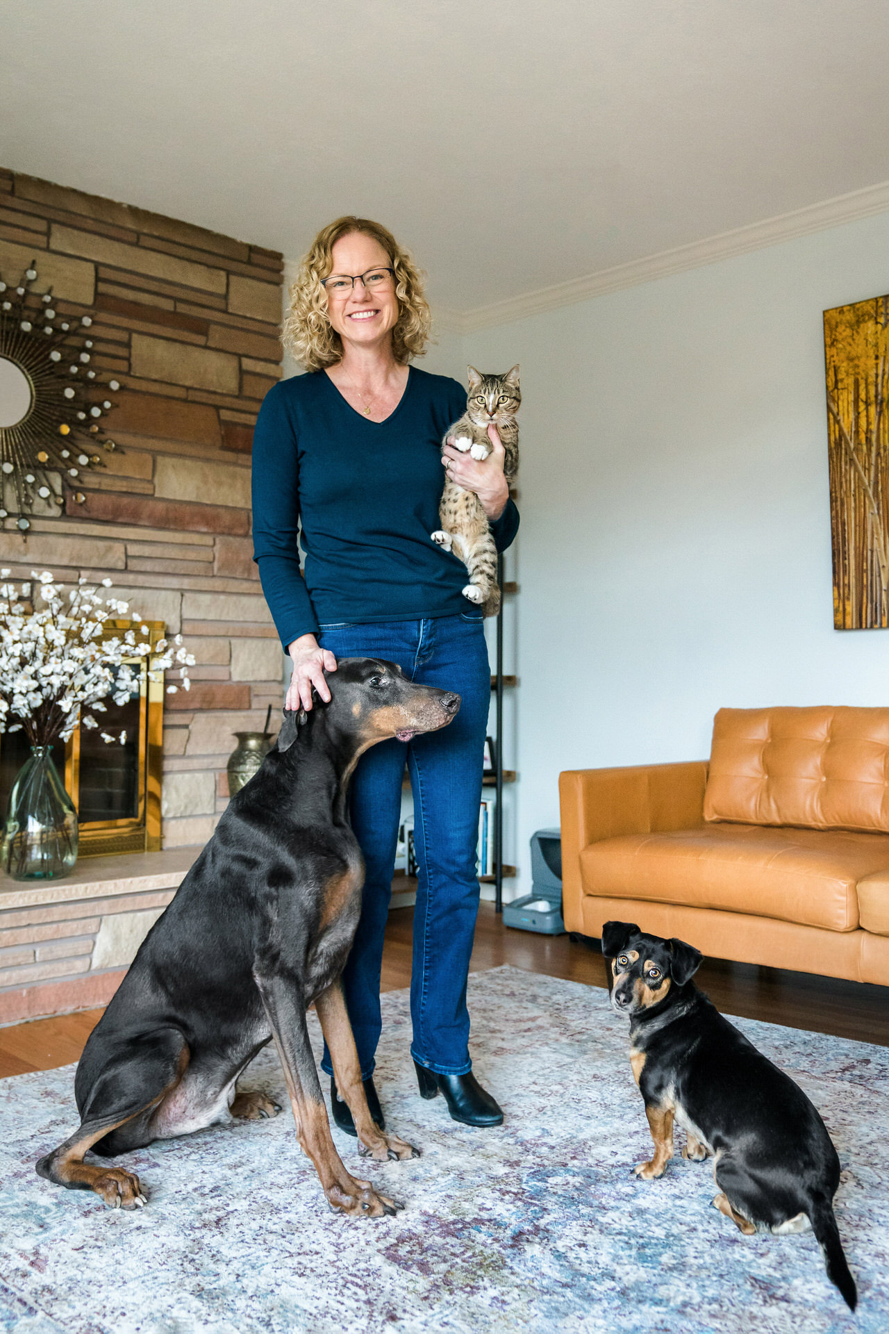 woman stands inside with her cat and two dogs
