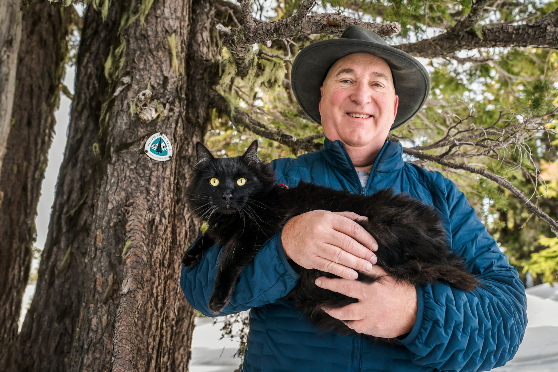 man holding cat by Pacific Crest Trail sign