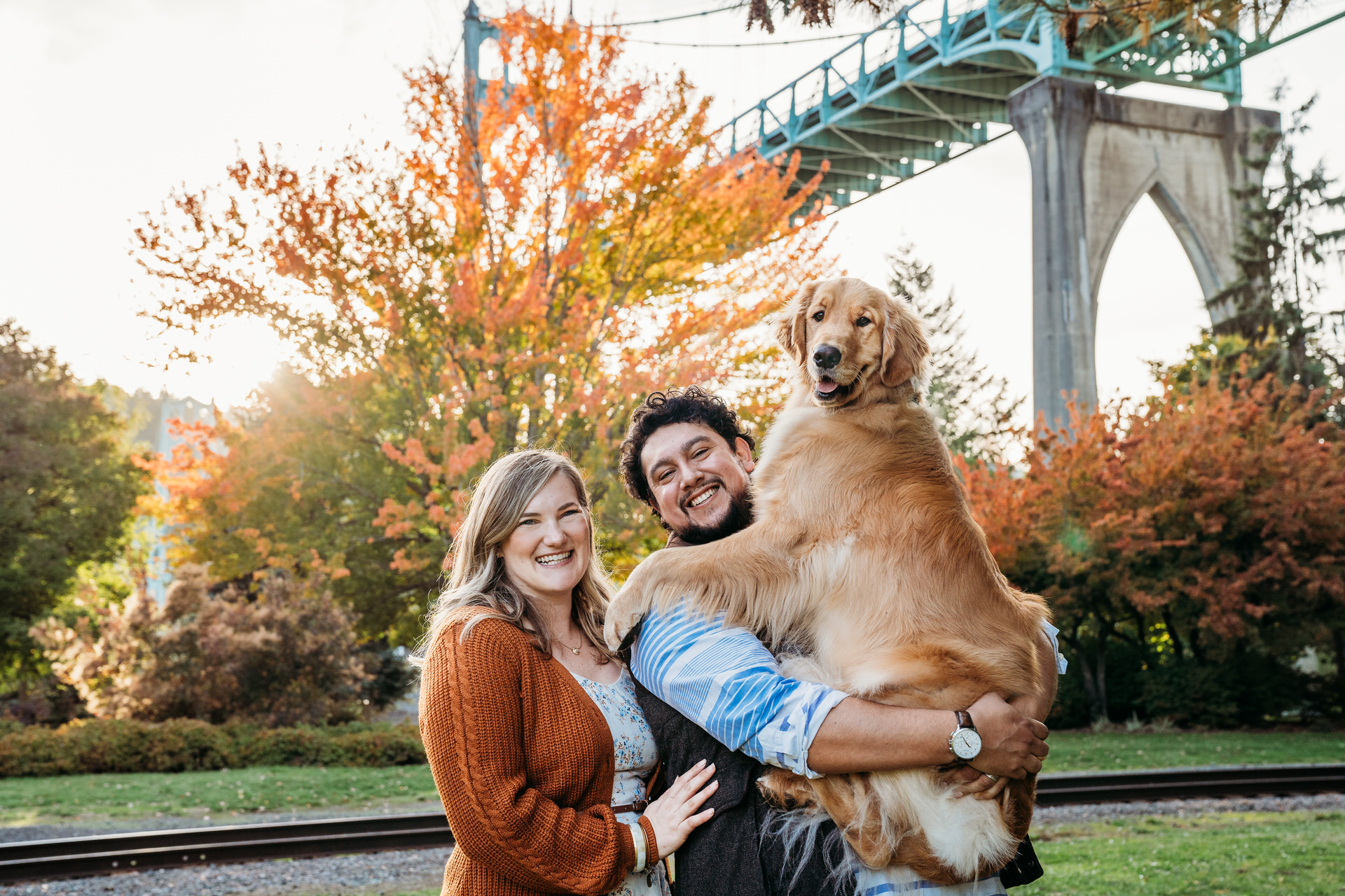 couple holds up golden retreiver at best park for fall photo session in Portland