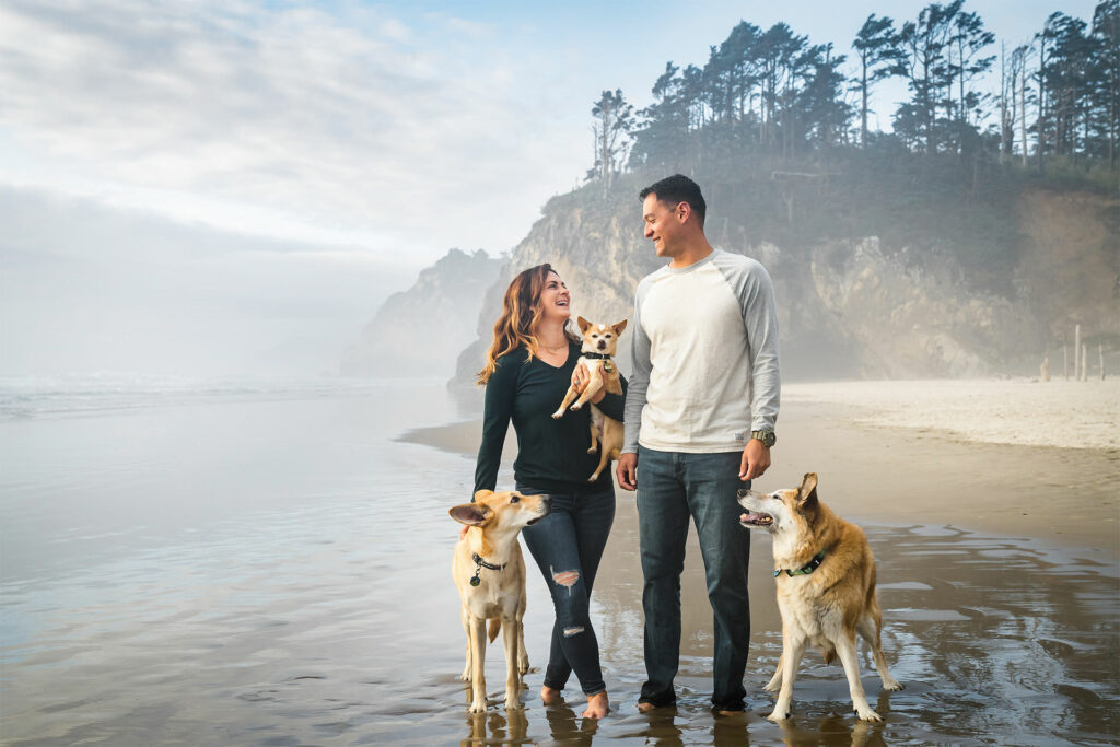 Happy couple on the Oregon Coast beach with their three dogs