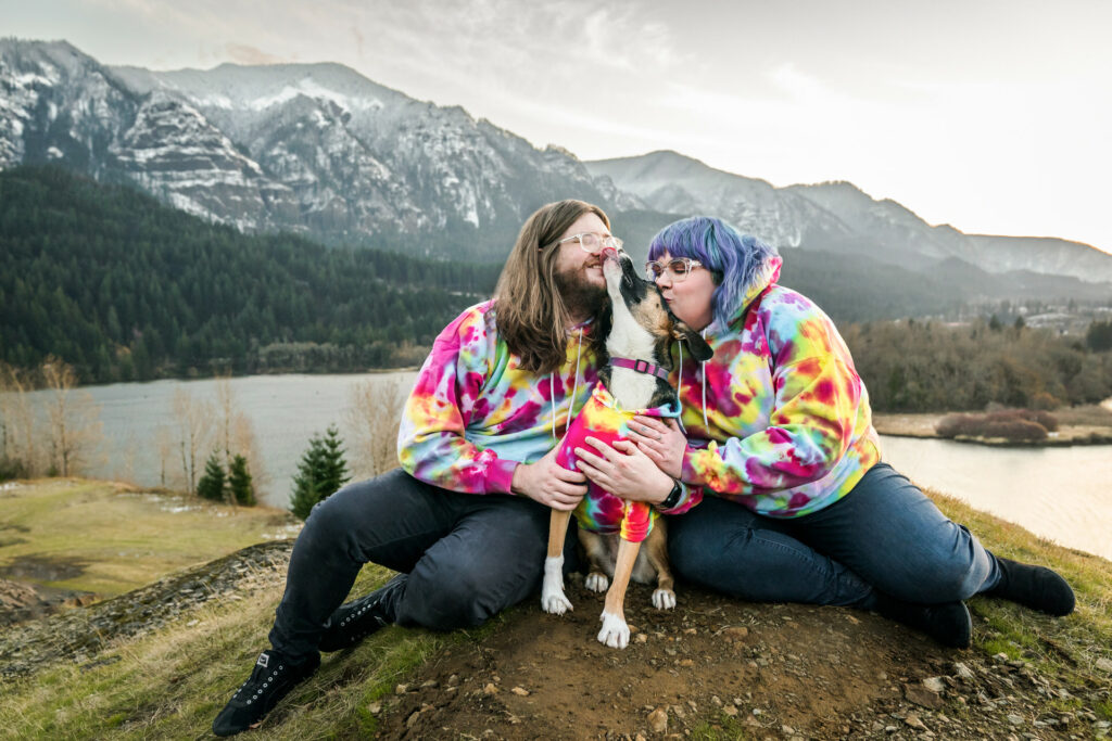 Couple wearing colorful outfits that match with their dog sit in a beautiful place