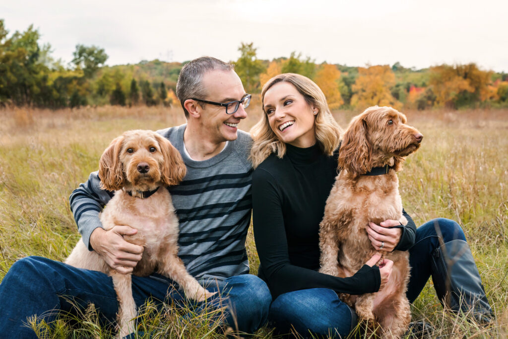 couple sits with their dogs in the autumn