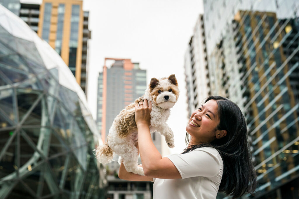 woman holds up dog in front of the amazon spheres building in downtown Seattle