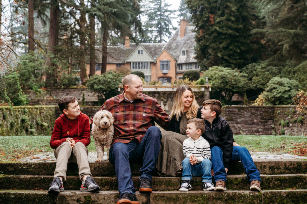 Family sits on steps at Lewis and Clark college with their dog