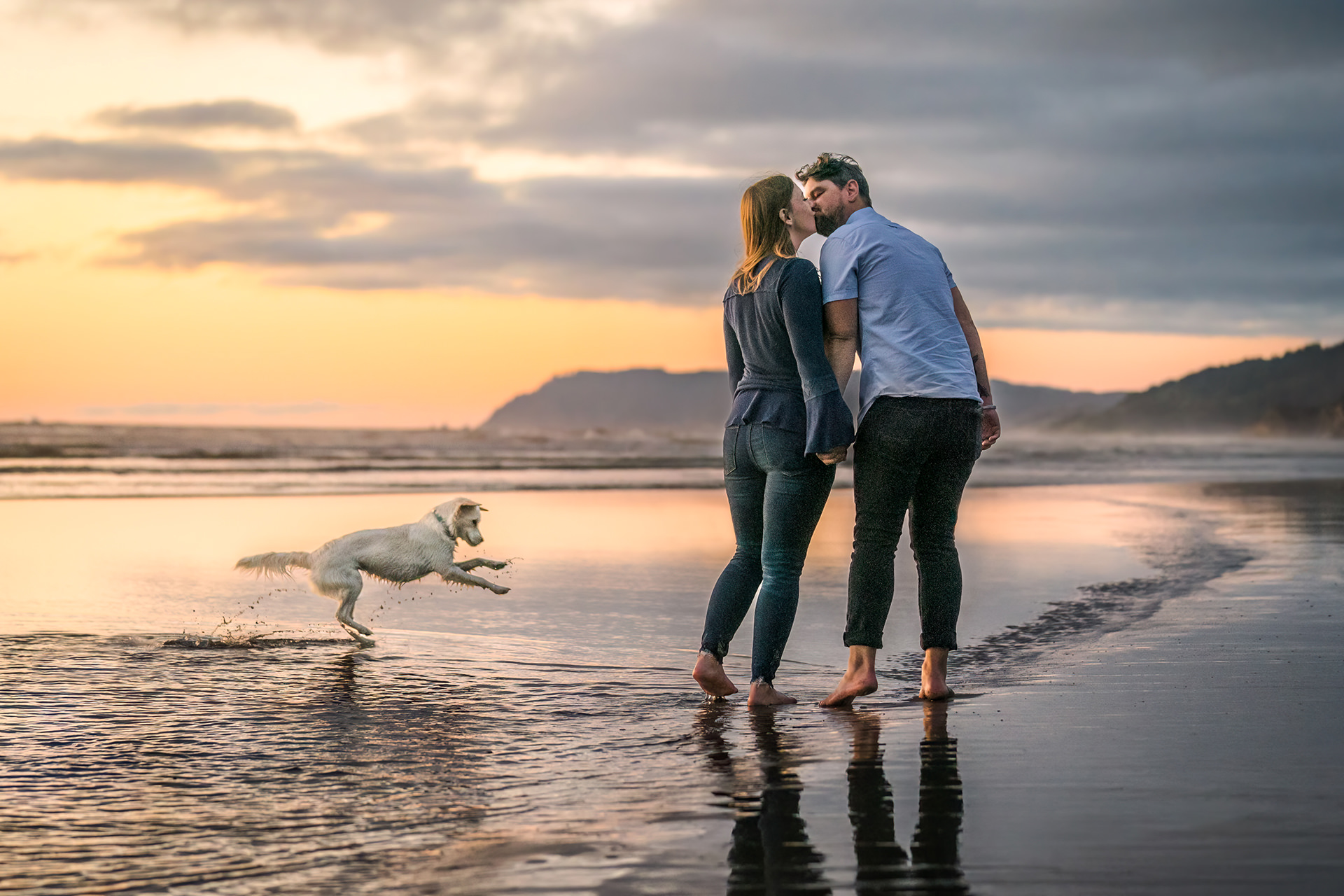 couple with dogs running on the beach