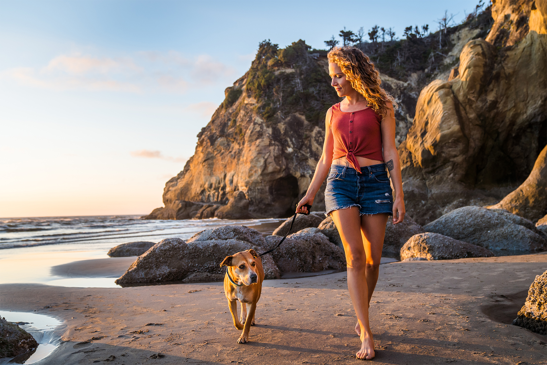 woman walks with her dog at sunset on the oregon coast