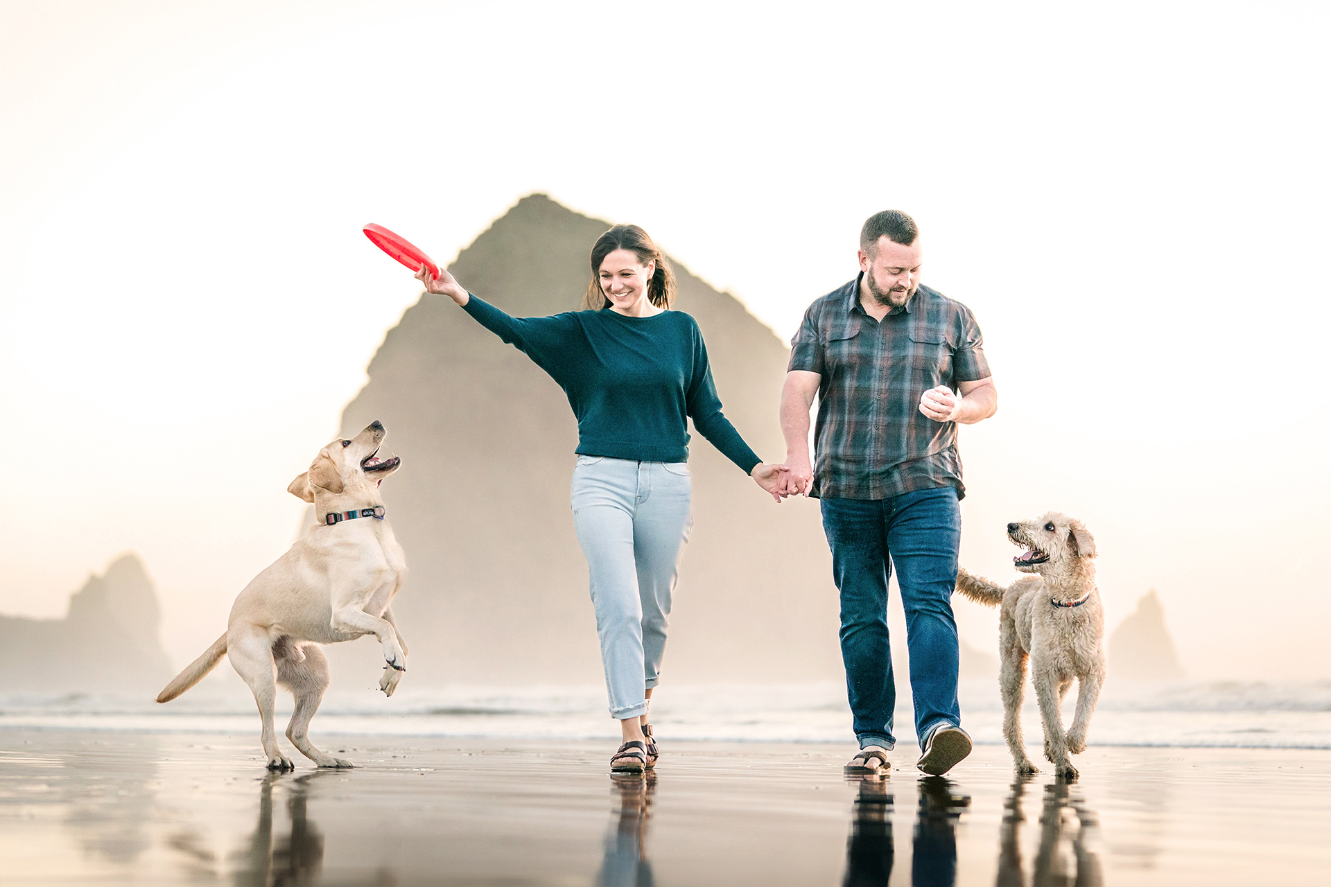 couple with dogs in front of Haystack Rock in Cannon Beach 