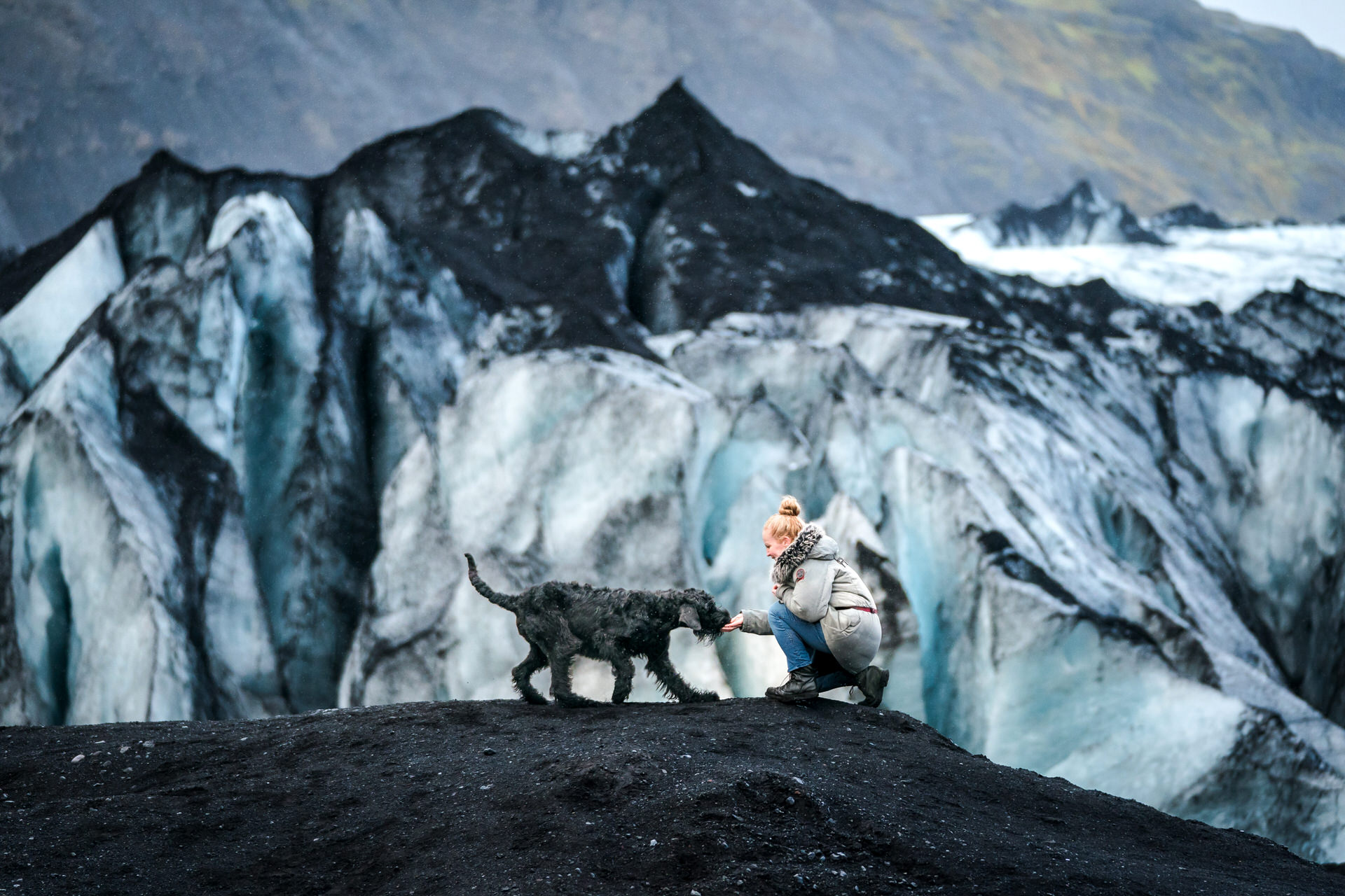 Person with dog by glacial ice formations at Sólheimajökull Glacier in Iceland